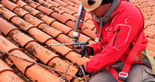 Verticales para Tejados en Segovia 4 Técnico aplicando sellador en tejado de tejas rojas durante reparación de goteras en Segovia