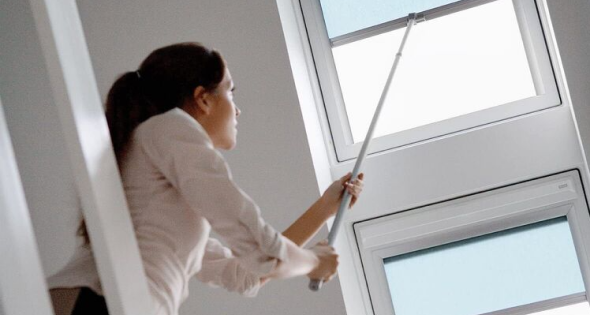 Instalación de ventanas velux en Segovia 4 Mujer abriendo una ventana Velux en el techo interior de su hogar en Segovia