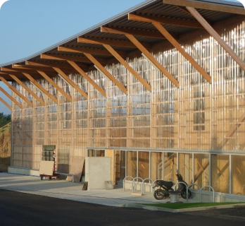 Onduline Bajo Teja en Segovia 14 Fachada con estructura de madera y paneles translúcidos en edificio industrial en Segovia