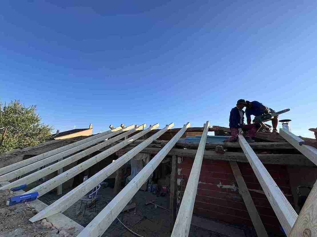 Obreros instalando vigas de madera durante la construcción de un tejado en Segovia