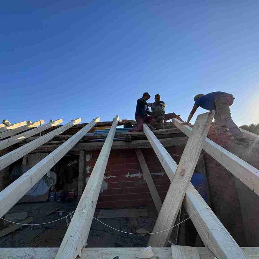 Sustitución de tejado nuevo en acción, con trabajadores instalando vigas en el tejado