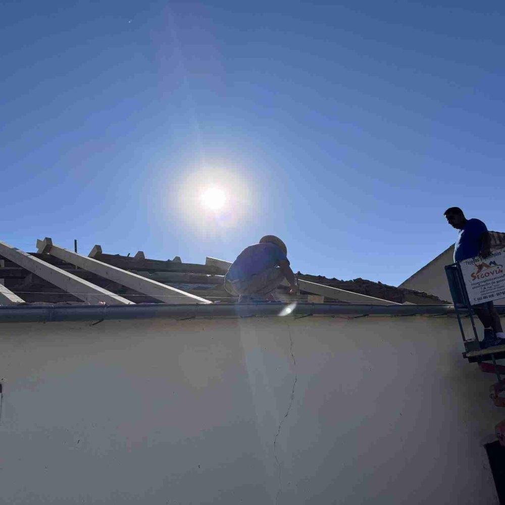 Sustitución de tejado nuevo, operarios en el tejado bajo el sol instalando las vigas
