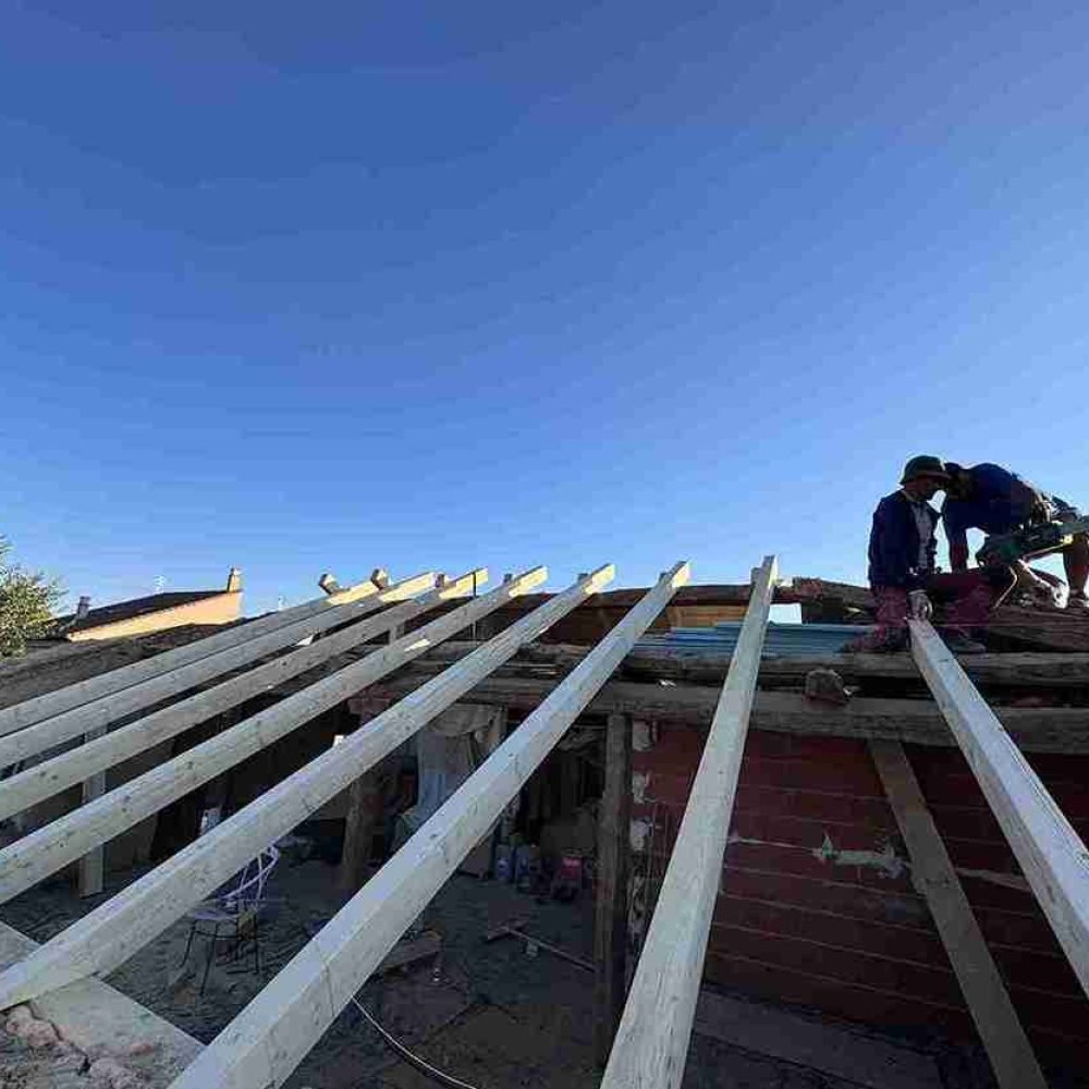 Obreros instalando vigas de madera durante la construcción de un tejado en Segovia