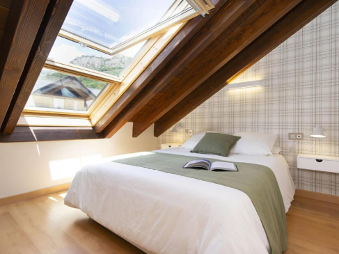 Reforma Buhardilla en Segovia 5 Dormitorio abuhardillado con claraboyas de madera y cama iluminada por luz natural en Segovia