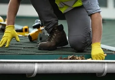 Inicio 9 Limpieza de canalones: técnico retirando hojas y suciedad en borde del tejado