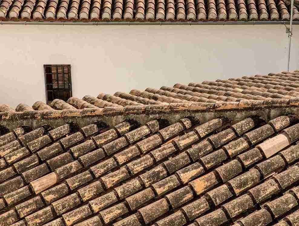Tejados de Teja: Guía Completa sobre Teja, Teja Cerámica, Mixto, Plana y Curvas para Cubiertas Duraderas 1 Vista superior de tejados de teja mixa con piezas envejecidas que muestran un estilo rústico y tradicional
